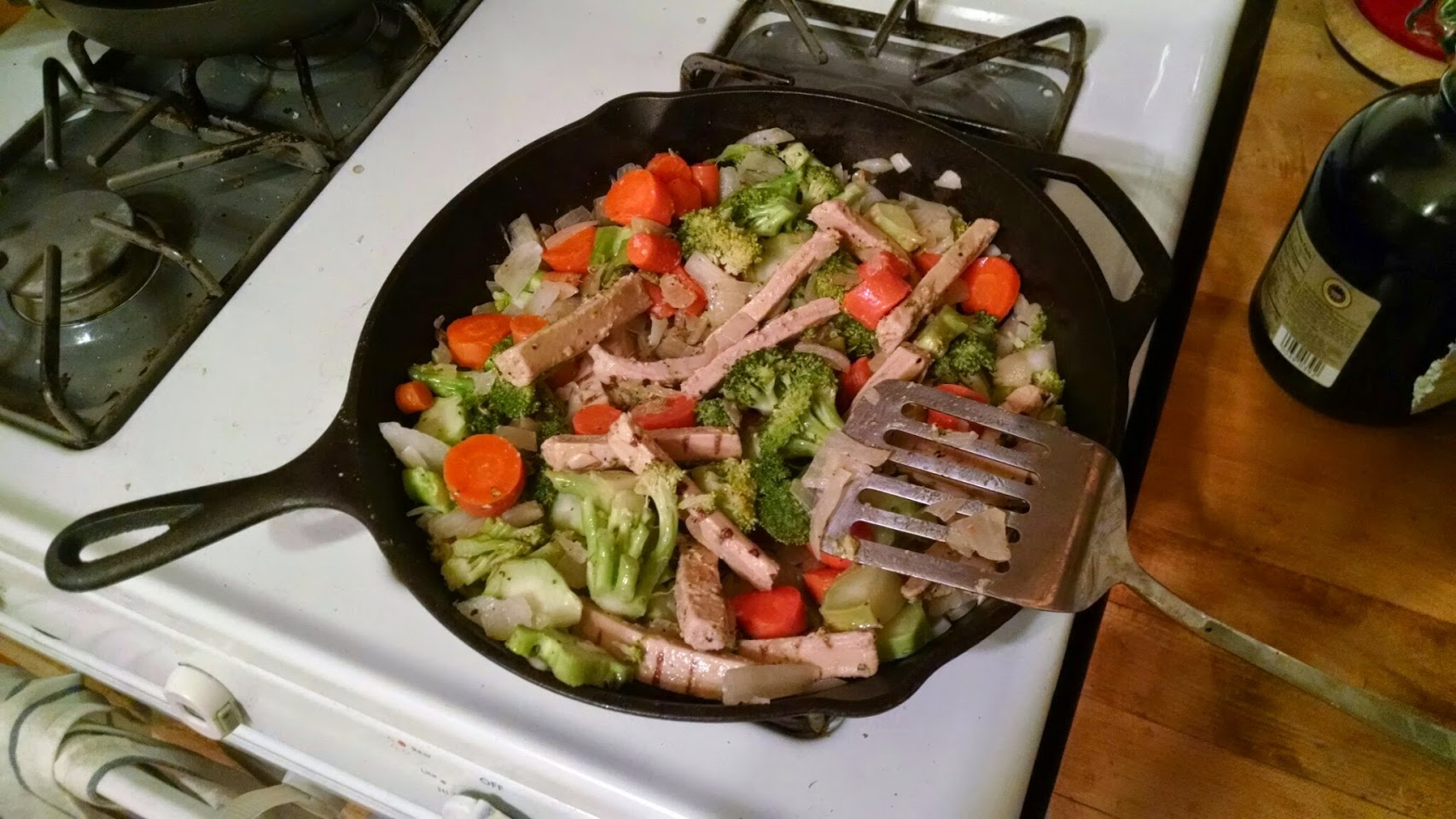 Broccoli, carrots, onion, and Beyond Chicken strips in a cast iron
